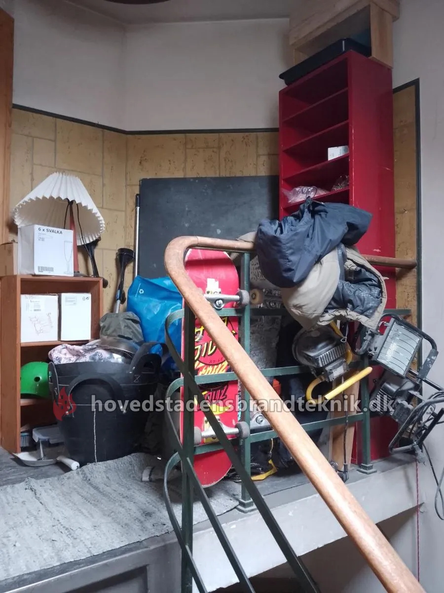 Reol, lampe, skateboard, tasker og kasser på reposen øverst på fortrappen