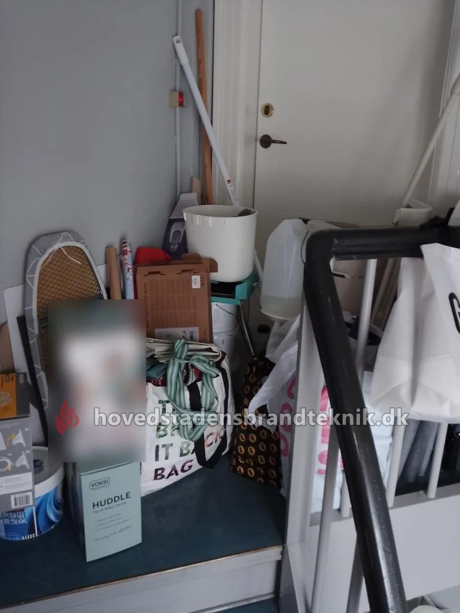 Strygebræt, papkasser, poser og dunke stablet på reposen på en bagtrappe